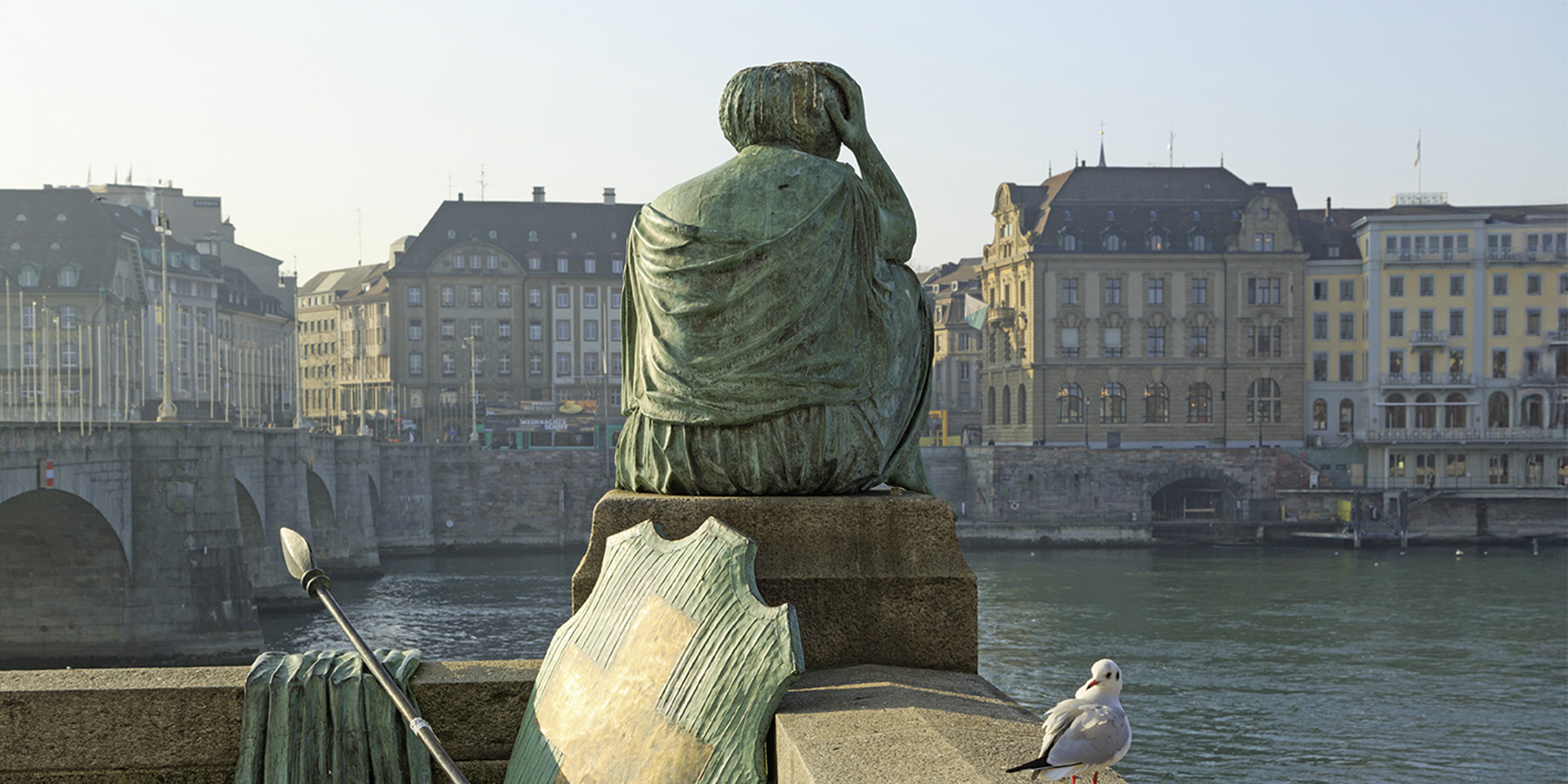 Nachdenkliche Helvetia-Statue mit abgelegtem Schild und Speer mit Blick auf den Rhein in Kleinbasel